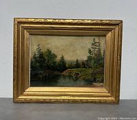 Front view of the framed painting showing the landscape scene with water and trees.