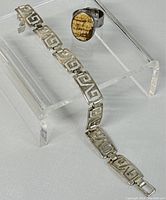Sterling silver bracelet and ring displayed on clear stand showing design and condition.