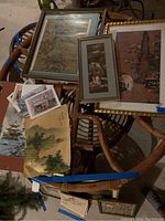 Photo showing three framed Asian prints under glass, two watercolor prints, and four cards with Asian-themed art on a wicker chair.