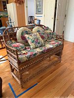 Full front view of bamboo loveseat with floral cushion and pillows