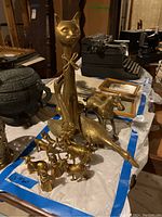 Overview photo showing the tall brass cat figurine surrounded by smaller brass animal figurines on a table.