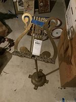 Full view of the brass music stand showing the lyre-shaped frame and base with claw-foot supports, along with the auction tag attached.
