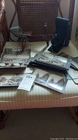 Overall view of the vintage camera, stereoview viewer, multiple stereoview cards and post cards placed on a striped cushion chair.
