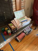 Candles arranged near a fireplace and on the floor, showing an assortment of colors and types including pillars and tapers.