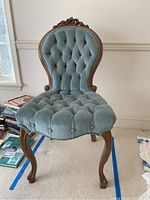 Side angle of velvet tufted chair showing wood legs and velvet upholstery.