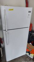 Front view of white Frigidaire top freezer refrigerator with visible handle and surface scuffs/stains.