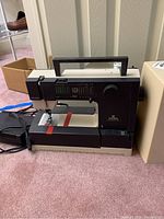 Side view of sewing machine showing stitch pattern display and control knob under handle.