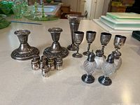 Overall view of two candlesticks, vase, cordial glasses and shakers arranged on counter