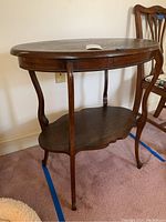 Full view of the oval wooden side table showing the shape, shelf underneath, and leg design.