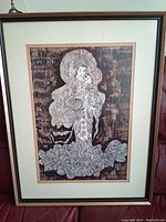 Full view of the framed art piece showing the woman holding a child with floral and textured background in monochromatic brown tones.