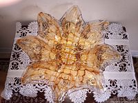 Top-down view of Murano glass bowl showing speckled golden coloring and flower petal shape edges on a lace tablecloth.