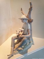 Front and side view showing full figure of boy reading book with dog beside seated by bare tree stump.