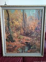 Full view of the oil painting in frame showing autumn forest scene with creek.