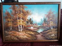 Full view of the oil painting showing a cabin by a river surrounded by autumn trees under a bright sky.