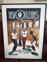 Framed serigraph artwork 'New Orleans, Jazz On Tap' showing a street scene with three boys playing and dancing, featuring Bourbon Street sign and stylized buildings.