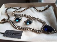 Photo showing vintage Austrian crystal necklace with blue teardrop pendant and matching earrings in a box with Austrian Crystal label.