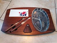 Top view of the full serving tray set including wood tray with floral tile, clear oval bowl, cheese knives, and wooden tool