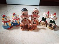 Image showing all eight vintage salt and pepper shakers together on floor, featuring clowns, gingerbreads, kissing elves, and squirrels.