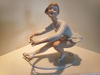 Front angle showing porcelain ice skater figurine with detailed facial features and skating pose.