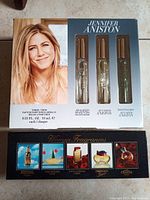 Box showing three Jennifer Aniston Eau de Parfum 10ml rollerballs and an image of Jennifer Aniston on the box front.