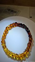 Front view of stretchy Baltic amber bracelet showing smooth, polished beads in gradient colors from yellow to dark amber