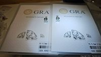 Two GRA moissanite report booklets with the pair of stud earrings on top
