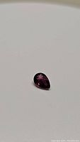 Top view of natural deep purple pear cut sapphire gemstone showing color and clarity.