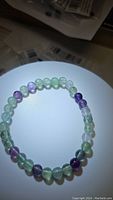Photo of natural rainbow fluorite stretchy bracelet showing round, polished beads in shades of green, purple, and clear strung on elastic.