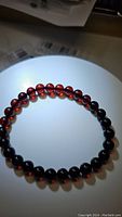 Close-up photo showing the stretchy bracelet composed of spherical blood red Baltic amber beads illuminated to reveal translucent qualities and rich color.