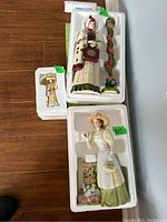 Three Avon Presidents Club dolls in original styrofoam packaging, showing poses and outfits for 2012/2013 and 2008/2009 dolls and smaller 2006 doll.