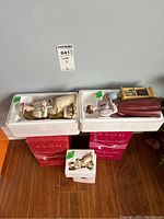 Three Avon Presidents Club dolls with original styrofoam inserts and red boxes, arranged on wooden floor against a wall.