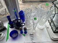 Overview of lot showing variety of crystal and cobalt blue glass items including pitchers, vases, teapot, bowl, and salt and pepper set.