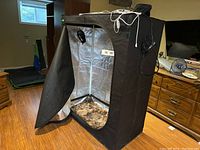 Black Doadan grow tent with the front zipper open, showing the reflective silver interior and dirty floor.