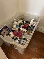 Bin filled with various boxed light bulbs and unpackaged bulbs of multiple types and sizes.