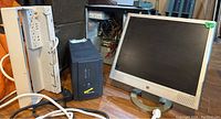 Photo of Vestapro 2000 UPS power supply, Belkin covered power bar, HP 29 inch monitor, and computer tower for parts on wooden surface.