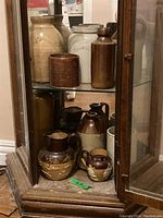 Bottom shelf showing five pitchers and jars with relief decoration and applied handles.