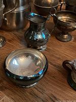 Photo showing a small silver plated pitcher and a round silver bowl with wide opening; both show patina and some tarnish.