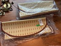 Six carpet stair treads new in packaging, beige with brown dash pattern and brown trim, stacked on a wooden surface.