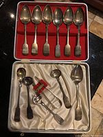 Open case showing six spoons in upper compartment and five spoons with sugar tongs below