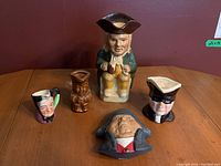 Overview of all six figurines including Toby mugs, Bossons Mr. Bumble, and character mugs for lot context