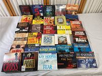 Photo showing spread of audiobook CDs from various authors like James Patterson, Lisa Scottoline, Michael Connelly and others arranged in rows.