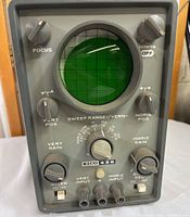 Front view showing circular CRT display and control panel with knobs and switches.