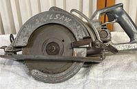 Side view of the 7 1/4 inch Skilsaw Super Duty circular saw showing metal body and blade with aging paint and use marks.