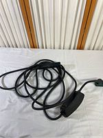 Overall view of Tesla charging cable with power adapter box on white background.