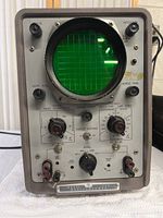 Oscilloscope front view showing CRT display and control panel with dials and switches