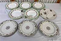 Front view of twelve assorted decorative porcelain plates on white surface, featuring three Haviland Limoges plates and other floral patterned plates.
