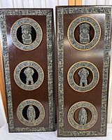 Front view of two rectangular wooden plaques each containing three circular insets with aztec-style resin figurines and decorative malachite resin borders within the frame.