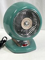 Front view of vintage teal Vornado heater fan showing round fan housing and grille.