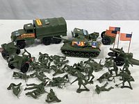 Full view of collection showing green army soldiers, transport truck, tank, cannons, and broken truck piece.