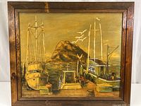 Full front view of the framed painting showing three docked boats and rocky background.